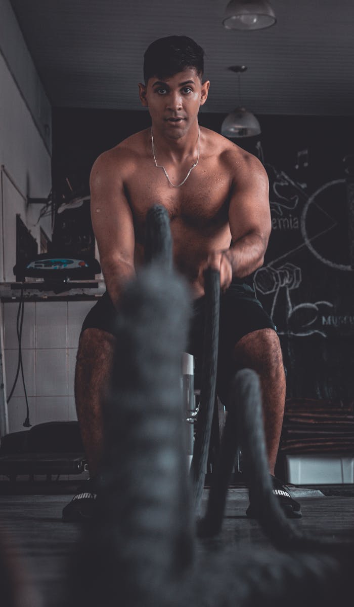 why-choose-us Fit young man working out with battle ropes in a gym setting.